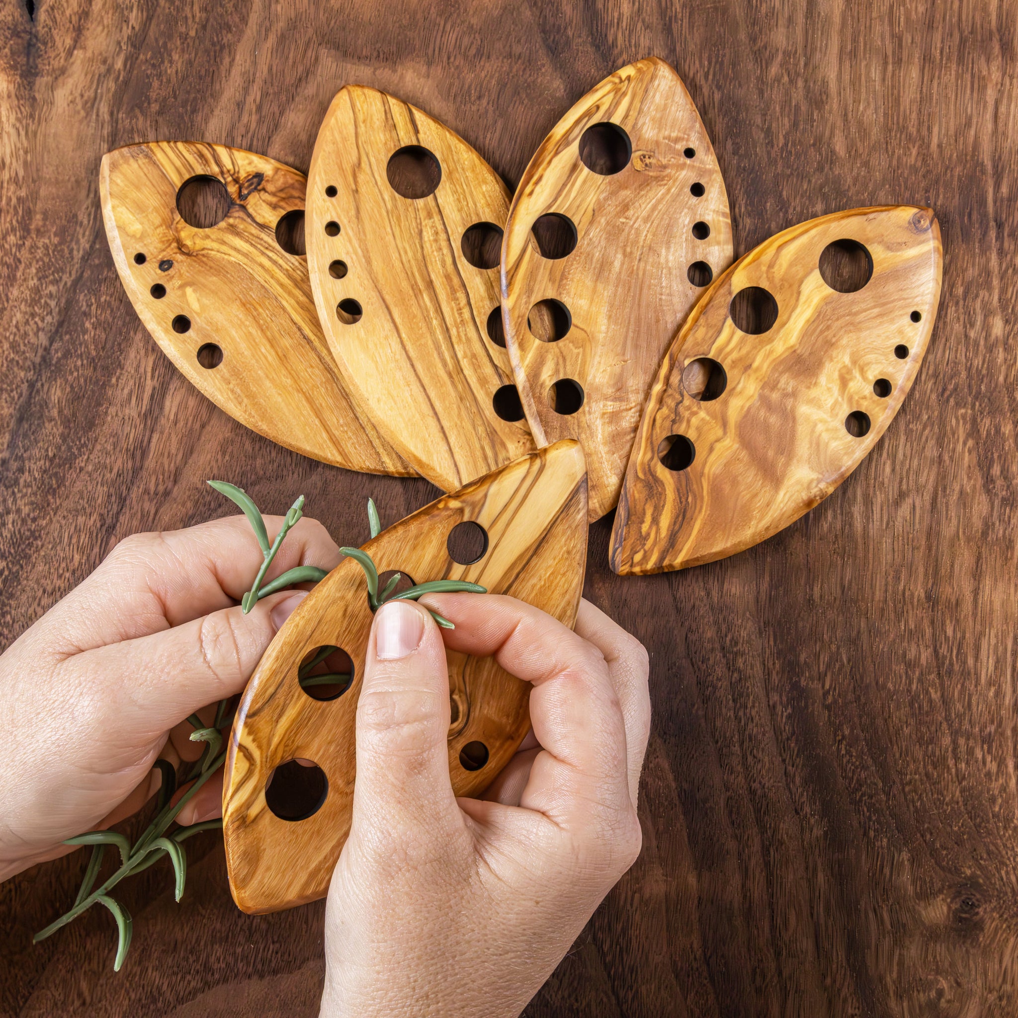 Wooden butterfly-shaped incense burner with hands holding a branch on a wooden background